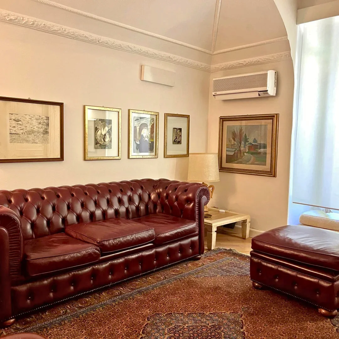 Accogliente sala d'attesa dello studio dentistico con divano chesterfield bordeaux e quadri